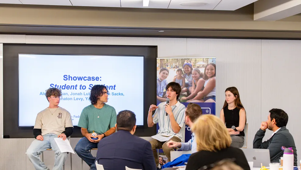 Four young people sitting on chairs presenting to an audience