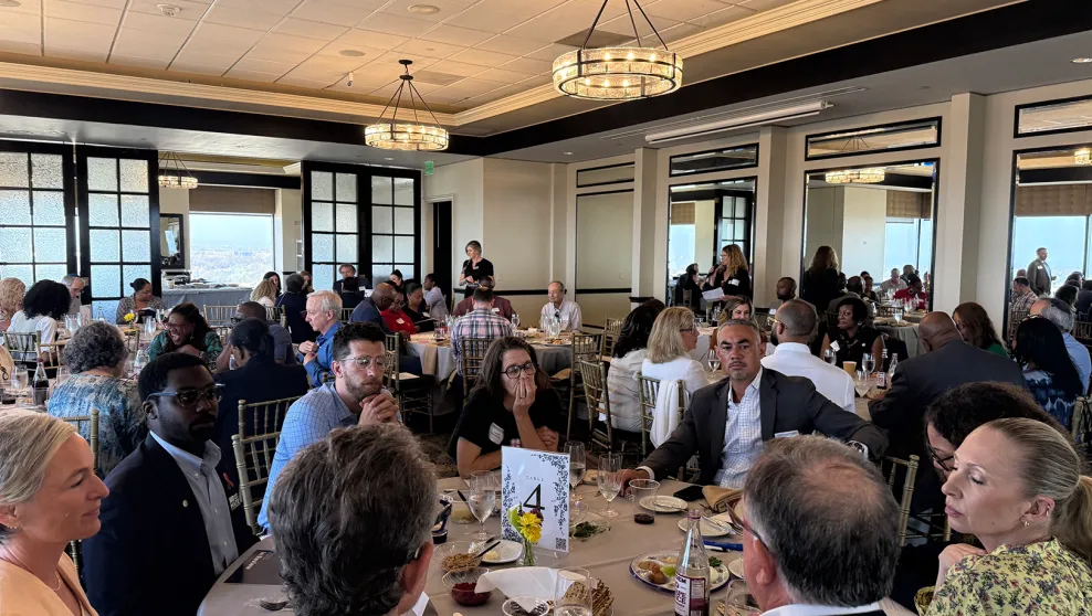 Groups of attendees seated around tables, engaged in thoughtful discussions